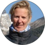Close up image of Jane Wilson smiling. The background shows a glimpse of the Antarctica landscape behind her.