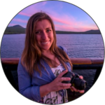 Image of Kelsey Bradley standing on the deck of a ship smiling. In the background, a purple blue evening sky spans the horizon.